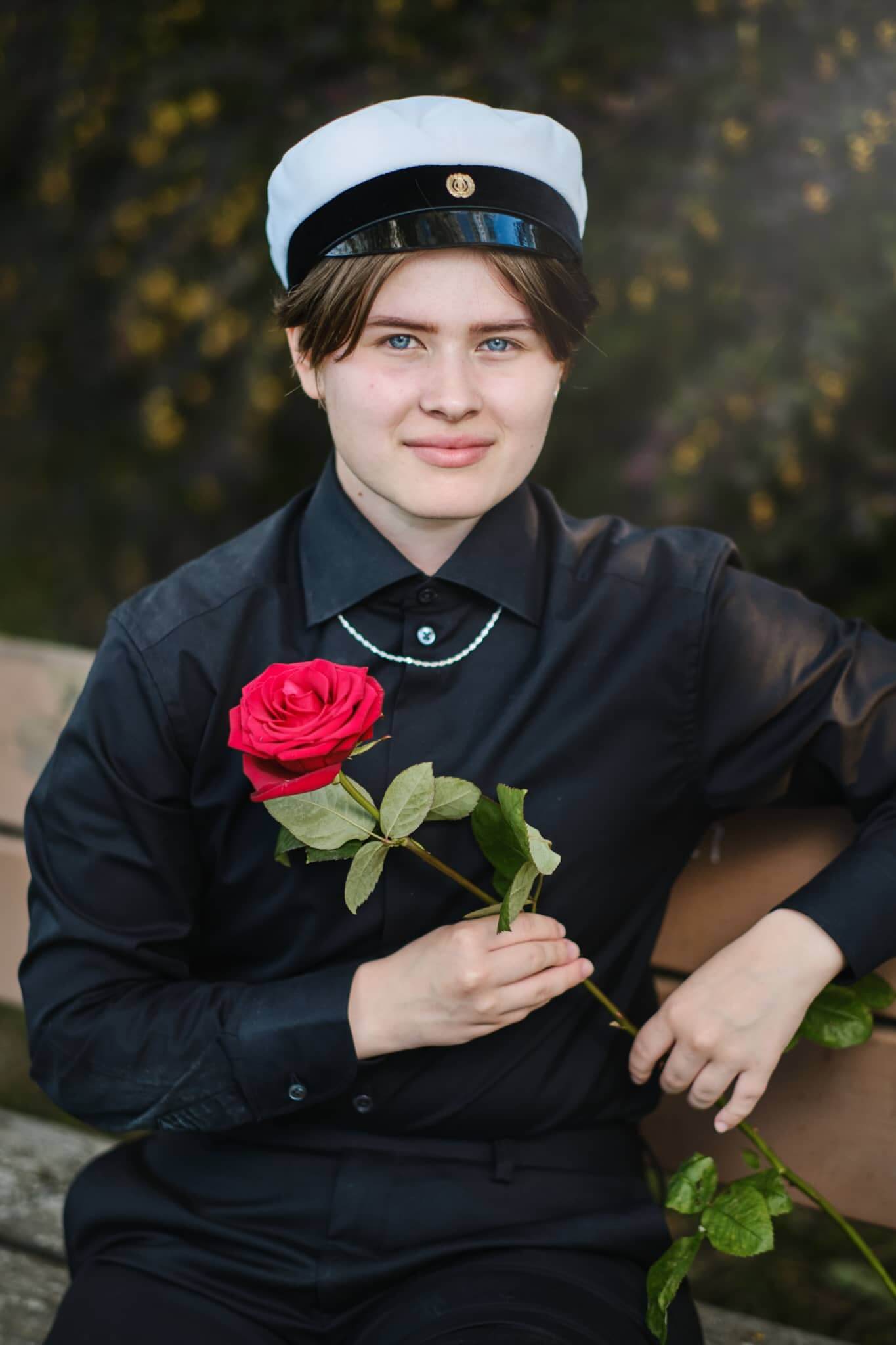 Ylioppilaskuva Jyväskylä Naissaaressa istuen penkillä ruusun kanssa