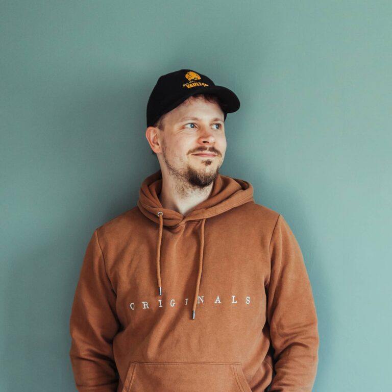 Jyväskyläläinen graafikko Niklas nojaamassa iloisena seinää vasten