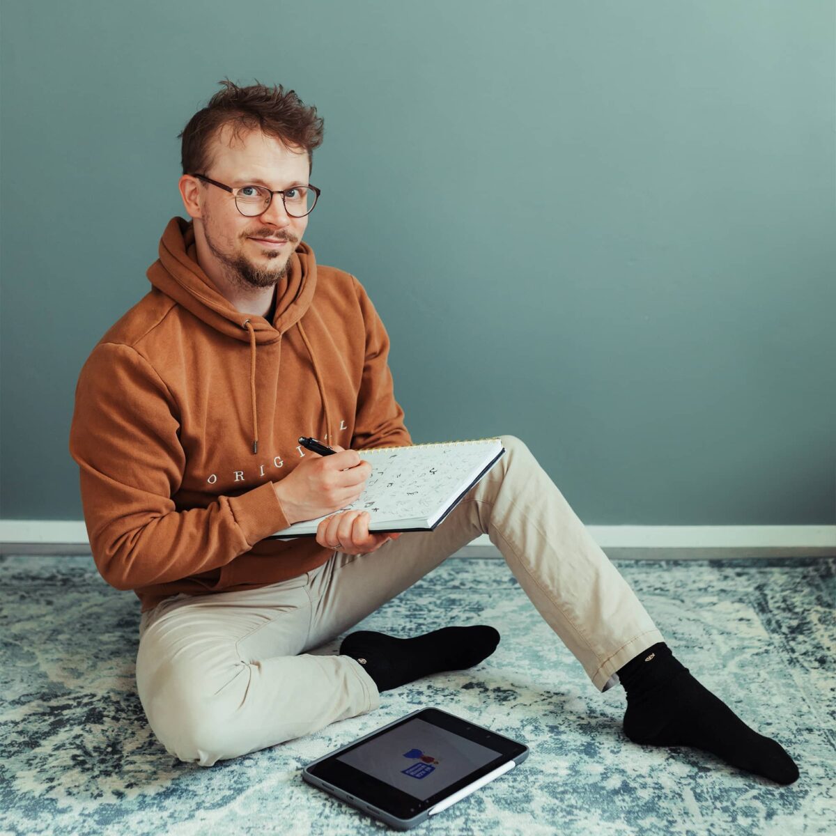 Niklas istuu lattialla piirtämässä paperille