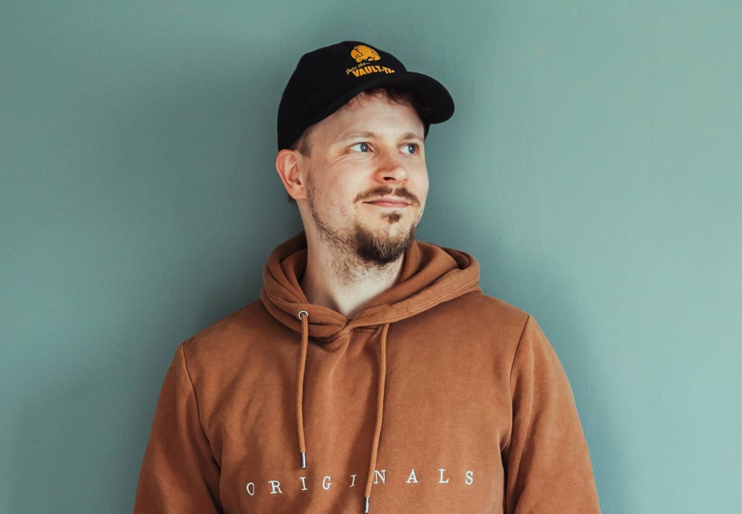 Piirtäjä Niklas Isberg nojaamassa iloisena seinää vasten